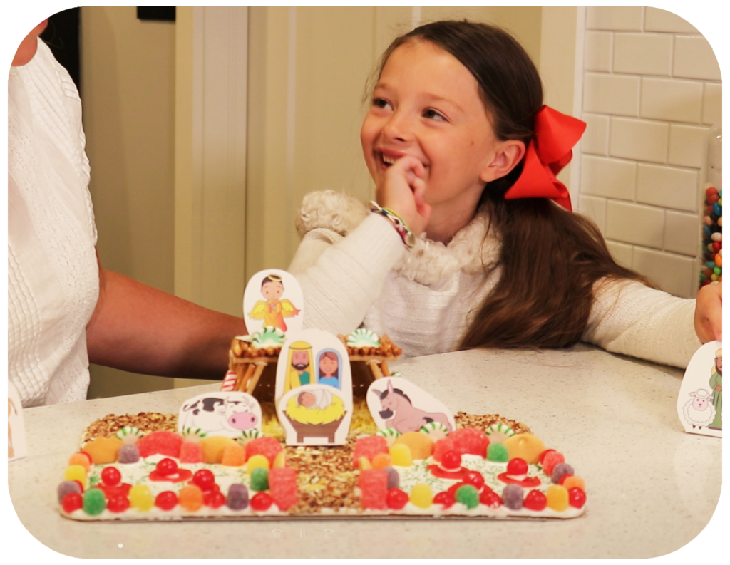 A young girl and mom builds and plays with a gingerbread nativity play set with mary joseph baby jesus and angel shepherds a cow and candy